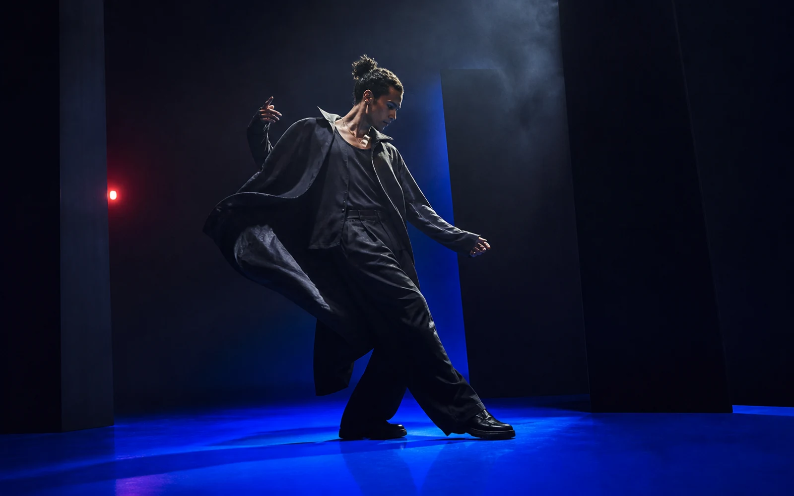 Original Acend campaign study of a performer moving through a cobalt-lit soundstage